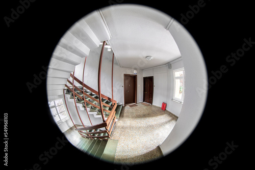Empty corridor, floor, stairways and two neighboring doors are visible through the door peephole 