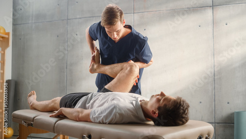 Advanced Sport Physiotherapy Specialist Stretching and Working on Muscle Groups or Joints with Young Male Athlete. Fit Sportsman Recovering from Mild Injury, Undergoing Rehabilitation.