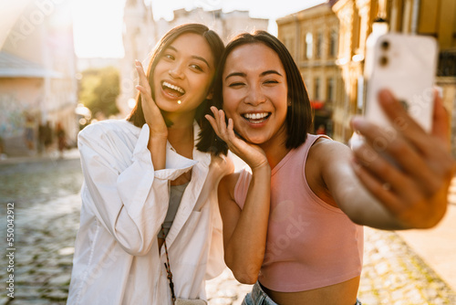 Two young beautiful smiling happy asian girls taking selfie