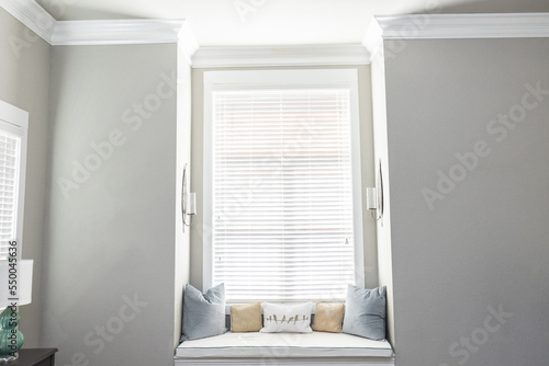 A light and bright gray master bedroom with a window seat for reading and relaxing