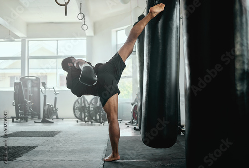 Professional, fit and active male fighter training with a punching bag in a gym. kickboxer practicing, training and fitness exercise for competitive fight, tournament or competition in a health club