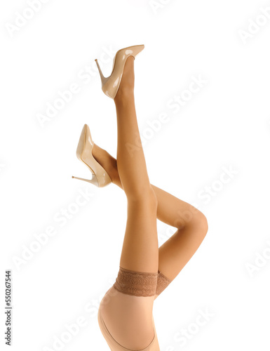Legs of beautiful young woman in beige stockings on white background