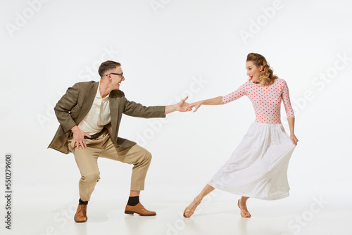 Young excited man and woman in 60s american fashion style clothes dancing retro dance isolated on white background. Music, energy, happiness, mood, action