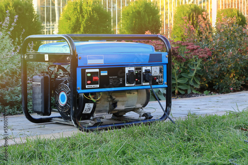 Power generator standing in the garden on the pavement. Agregat prądotwórczy stojący w ogrodzie na chodniku.