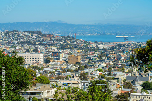Sprawling downtown san francisco california with hazy mountain with blue sky and ocean background and urban trees