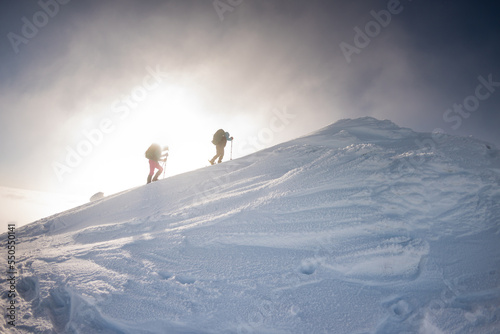 two climbers climb the mountain. Two girls climb a snow-covered mountain.