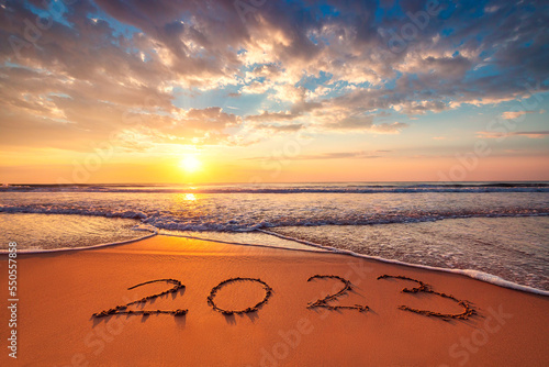 Happy New Year 2023 ocean sunrise on the beach shore concept