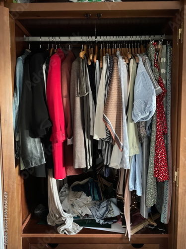 open closet with clothes on hangers. Piles of delicate clothes hung tightly together.
