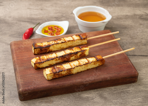 Grilled Rennet or Coalho cheese on a wooden board with sugar syrup and pepper
