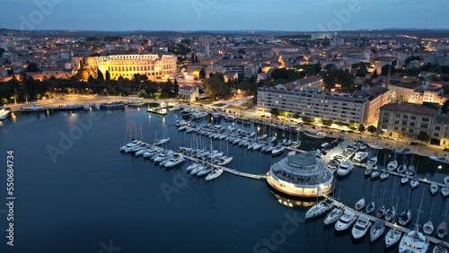 town harbour Pula with roman amphitheatre at night, aerial view