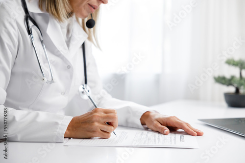 Woman medic, doctor writes out a prescription. Makes an entry in the medical record. Medical background.