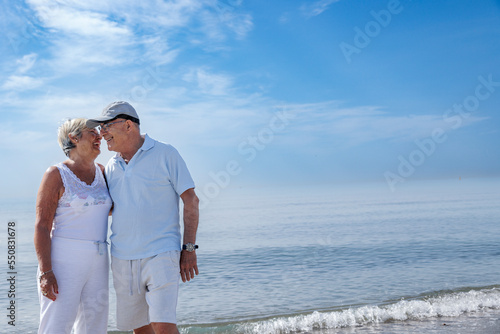 coppia di anziani coniugi si abbraccia affettuosamente vicino alla riva in una spiaggia 