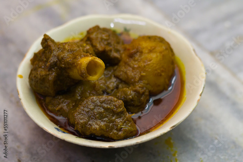 mutton curry and potato served in a bowl. the dish cooked in traditional indian style. spicy red gravy and potato is accompanied.photo taken with selective focus.
