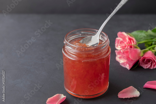 Bulgarian rose petal jam in a jar with spoon on black background with copy space