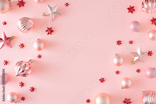 Christmas eve concept. Top view photo of Christmas baubles and stars on pastel pink background with copy space. Winter holiday card idea.
