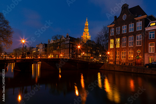 Romantic nocturnal view of Amsterdam: canal in the Red District. Buildings, cars and boats are reflected in the water