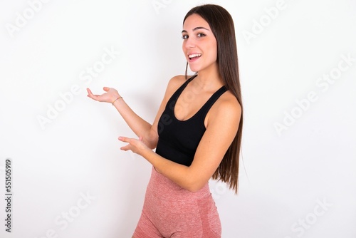 Young caucasian woman wearing sportswear over white background Inviting to enter smiling natural with open hands. Welcome sign.