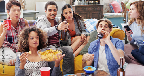 Friends, drink and snacks and watching tv, relax and beer in living room, diversity and sports together in home. Men, women and people watch television, sports and streaming subscription with alcohol
