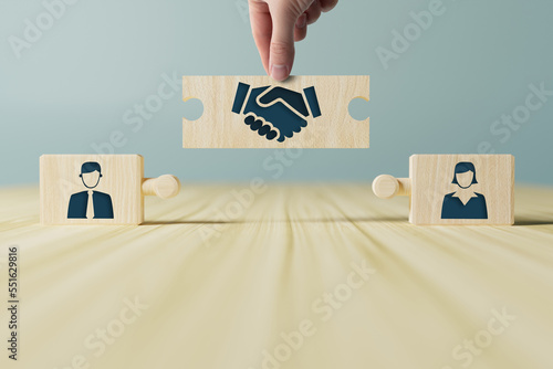 The hand holds wooden wooden blocks with icons of a woman and a man and shaking hands in the act of consent. The concept of divorce, agreement, mediation, the role of the mediator.