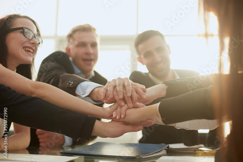 group of young business people joining their palms over a work Desk.