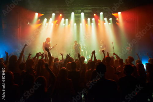 Rock, band and crowd of people at concert for stage performance, party dance and new year or holiday festival in dark. Dancing, singing and celebrity or musician with night club music for an audience