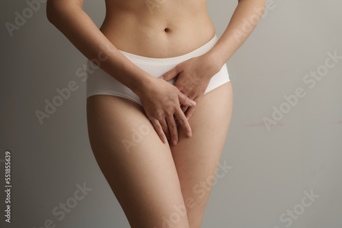 Close up asian woman cropped shot with white panties on grey background, vagina healthy concept.