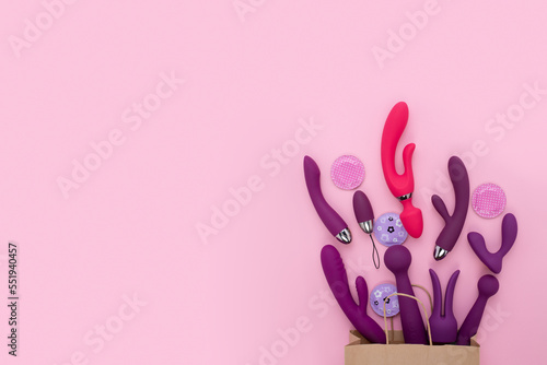 A paper shopping bag filled pink Purple silicone sex toys on a white background. Erotic toy for fun. Sex gadget and masturbation device. View from above. Place for text. Flat lay. Sex shop concept.