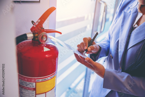 woman worker inspection chemical Fire extinguisher and fire hose. writing on monthly check document. Selected focus 