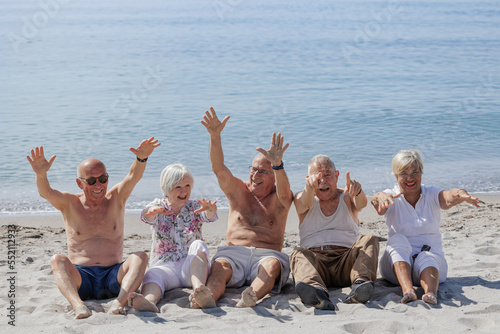 Un gruppo di anziani si diverte seduti nella spiaggia in riva al mare 