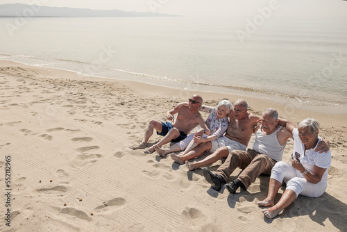 Un gruppo di anziani si diverte seduti nella spiaggia in riva al mare 