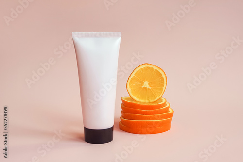 Mockup pink squeeze bottle cosmetic tube with screw black cap and orange slices on pink background. Lotion, moisturizer, balsam, hand cream, gel, skincare with vitamin c. Mock-up, front view