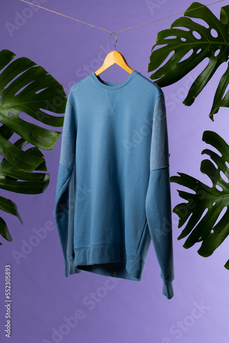 Sweatshirt hanging on coat hanger and copy space on purple background