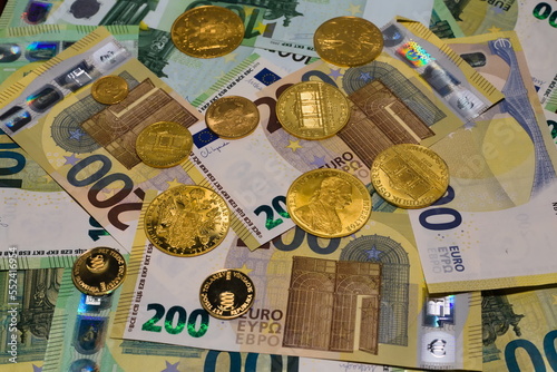 Arrangement of crisp 100 EUR and 200 EUR banknotes and gold coins