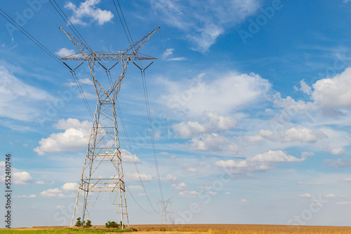 Electricity transmission towers in rural farm field. Electrical power grid and distribution safety, security and maintenance concept