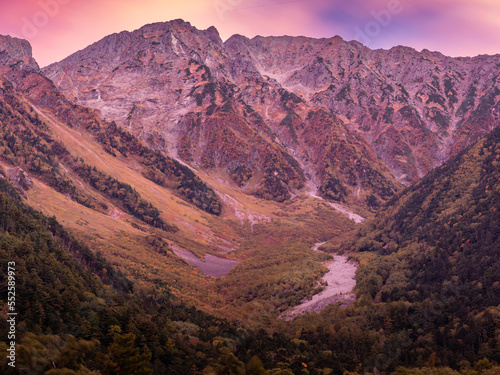 北アルプス山脈に日の出前の朝焼けで雲が色付き、山々も周囲もピンク色に染まる。