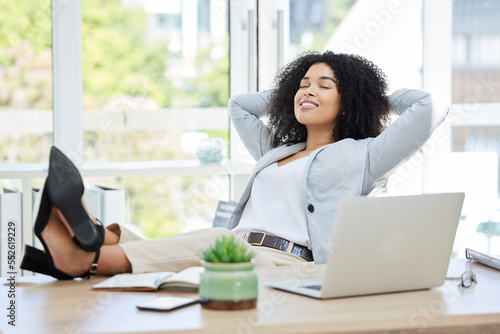 Business woman, feet up and relax with laptop on office desk while happy about productivity, success and career choice as boss, leader or manager. Black female entrepreneur done and finish with work