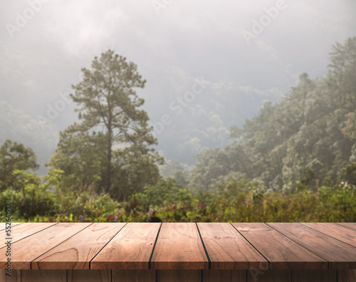 Wooden table top with mountain landscape and pine forest, for display product.