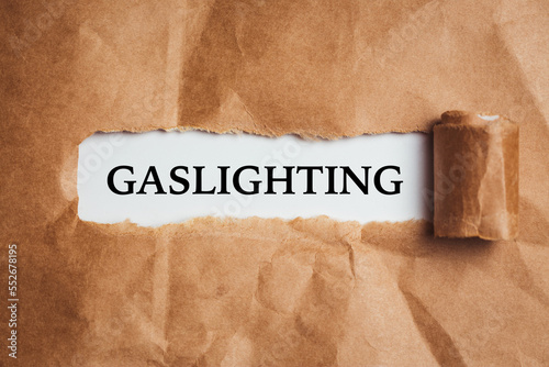 the word Gaslighting appearing behind torn brown paper. 