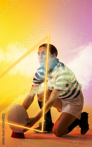 Illuminated triangle over caucasian female player placing rugby ball on stand amidst smoke