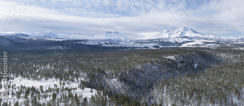 aerial drone of snow covered mountains and forest in winter