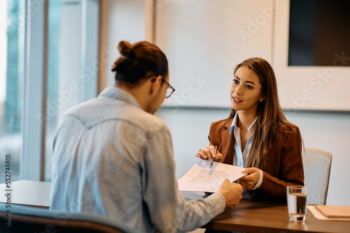 Young bank manager going through agreement with her client during meeting in office.