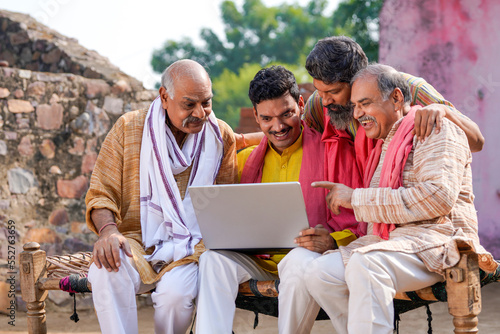 Indian villagers setting at in front of home and using laptop.