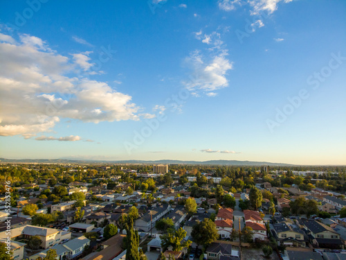 aerial shot of majestic mountains with powerful clouds and blue sky with homes, apartments and lush green trees in Monrovia California USA