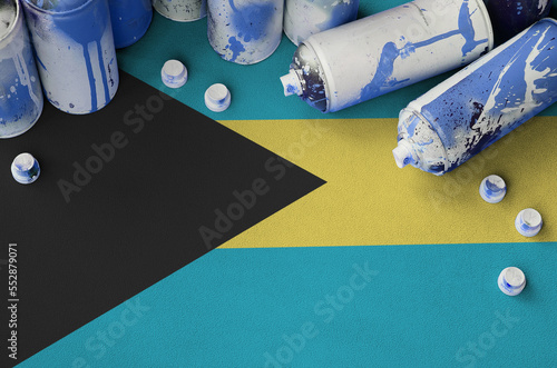 Bahamas flag and few used aerosol spray cans for graffiti painting. Street art culture concept, vandalism problems