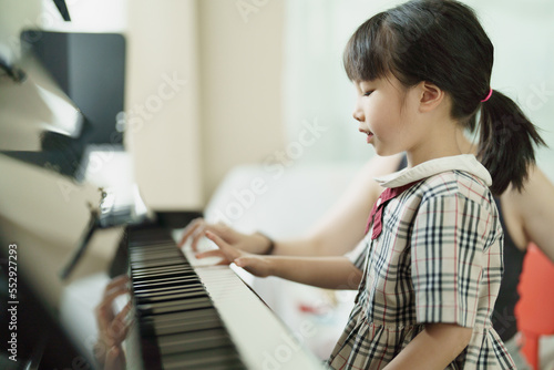 Asian girl kid learning or practicing piano at school.