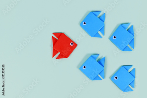 Paper fish swimming swimming against the current in other direction than different colored fish