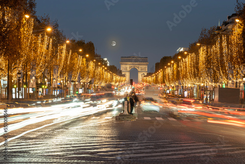 Paris - France,France - 12 08 2022: View of the Arc-De-Triomphe and Avenue des Champs Elysees with Christmas lights and full moon