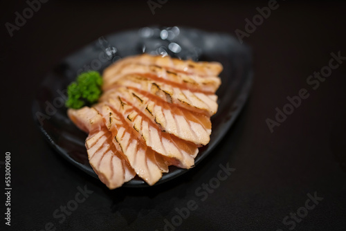 Roast sashimi salmon made by gas burner on black disk