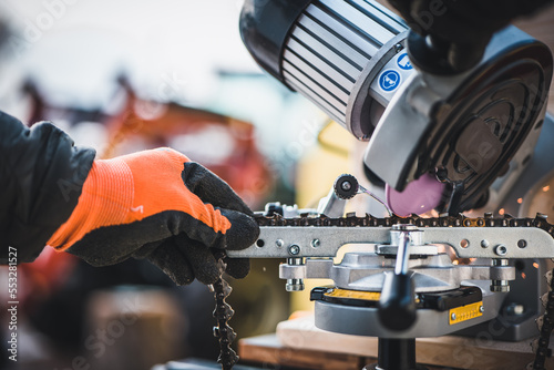 Sharpening motor chain or chainsaw chain with the use of a motorized grinder. Professional repairman sharpening a chain. Sharpening a chainsaw.