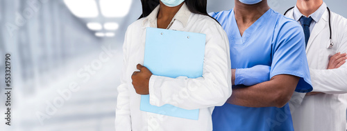 Medical Services. Multiethnic Group Of Doctors In Uniform Posing In Hospital Corridor